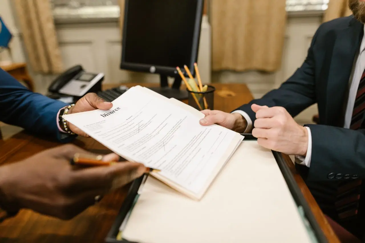 Un document remis d’une main à l’autre au-dessus d’un bureau