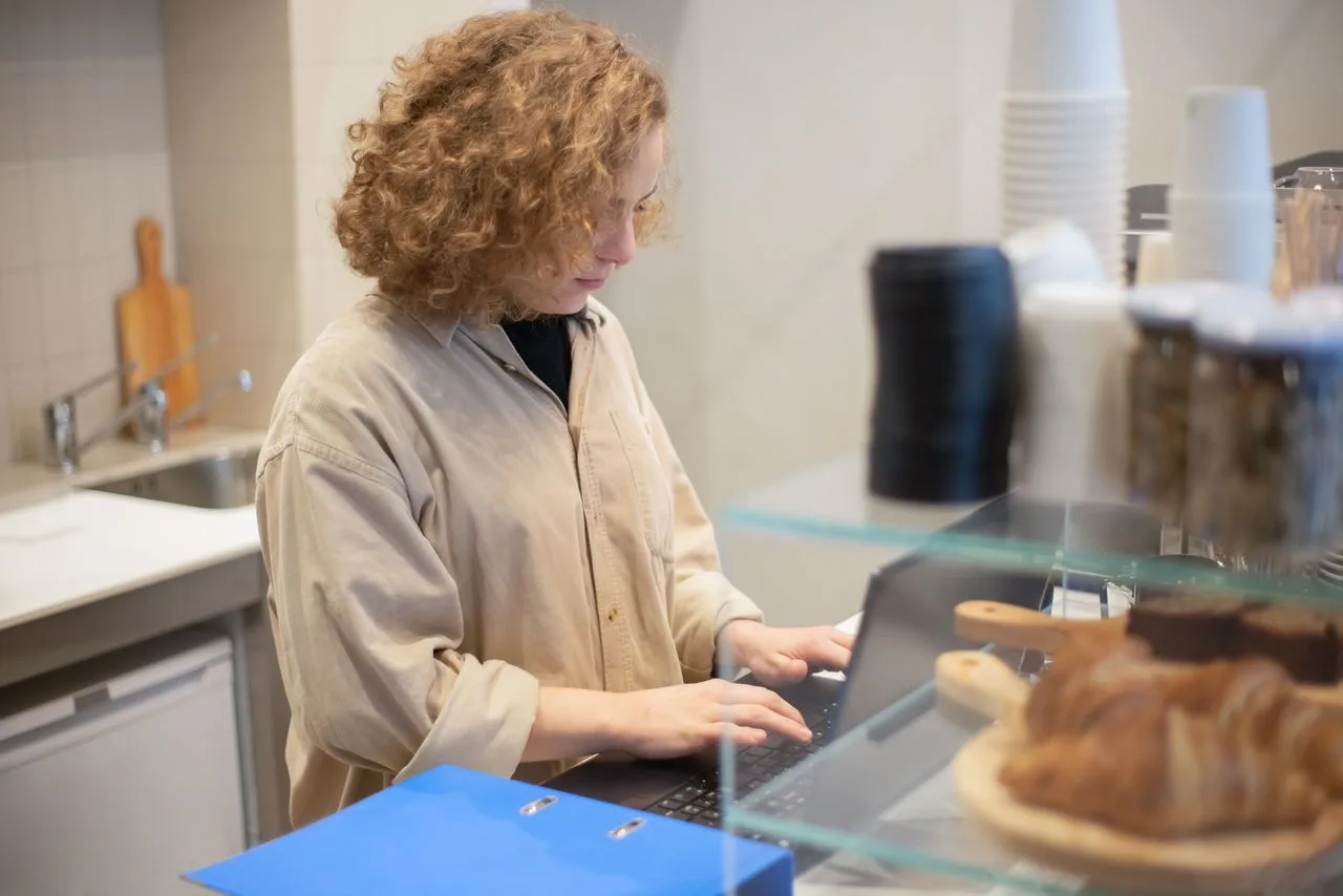 Une commerçante indépendante fait son administratif derrière son comptoir
