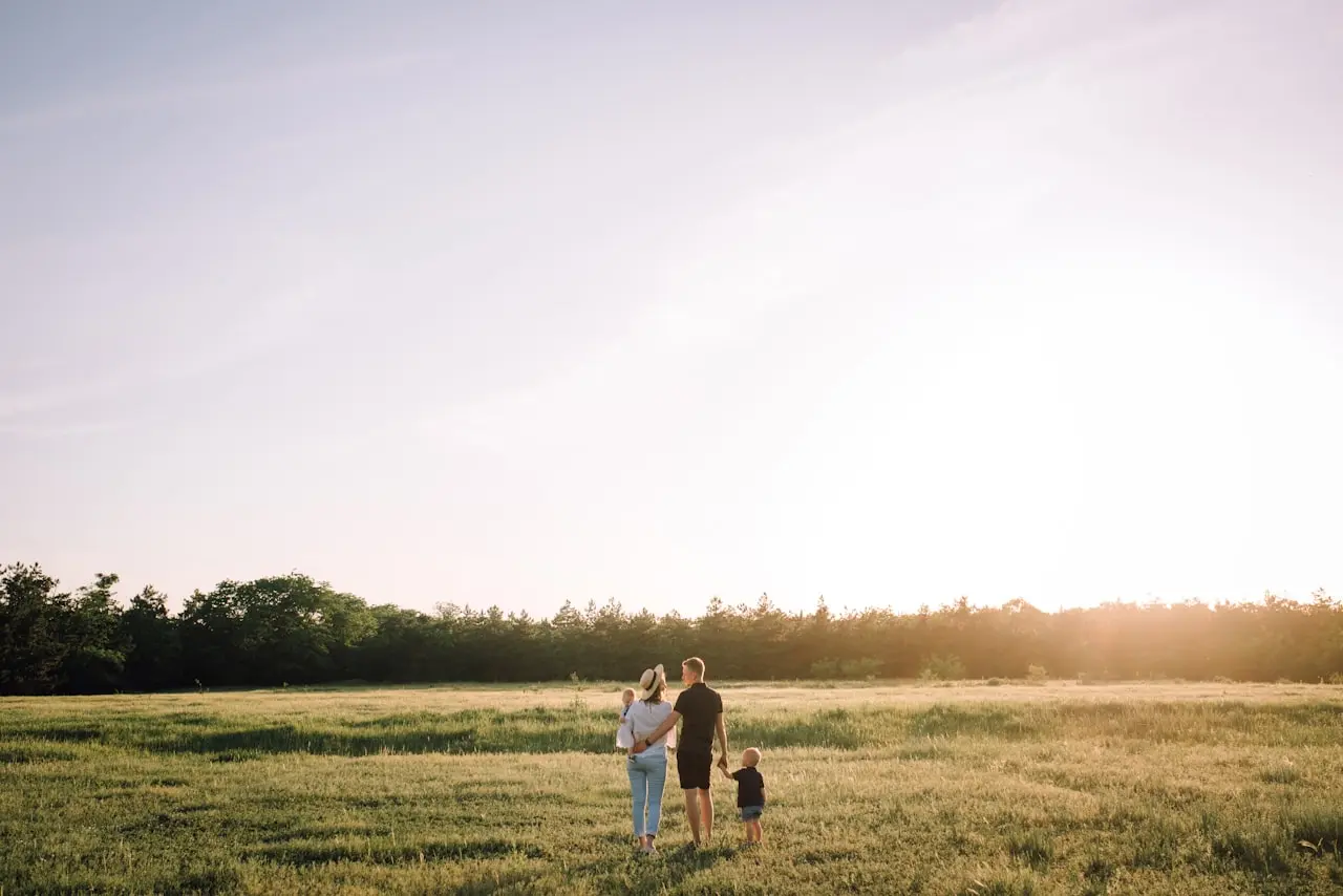 Une famille marche dans un champ au coucher du soleil
