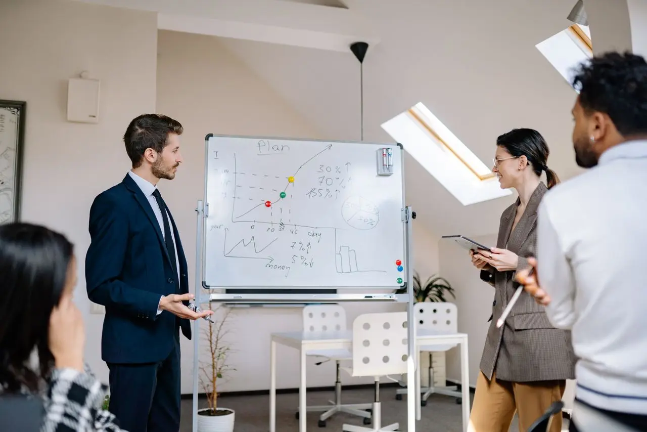 Réunion de travail devant un tableau blanc couvert de projections chiffrées