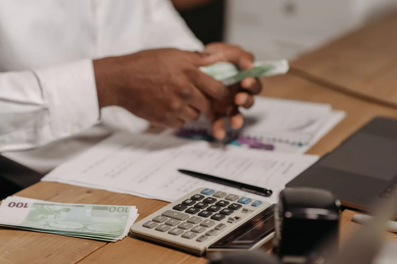 Des mains comptent des billets en euros au-dessus d'un bureau