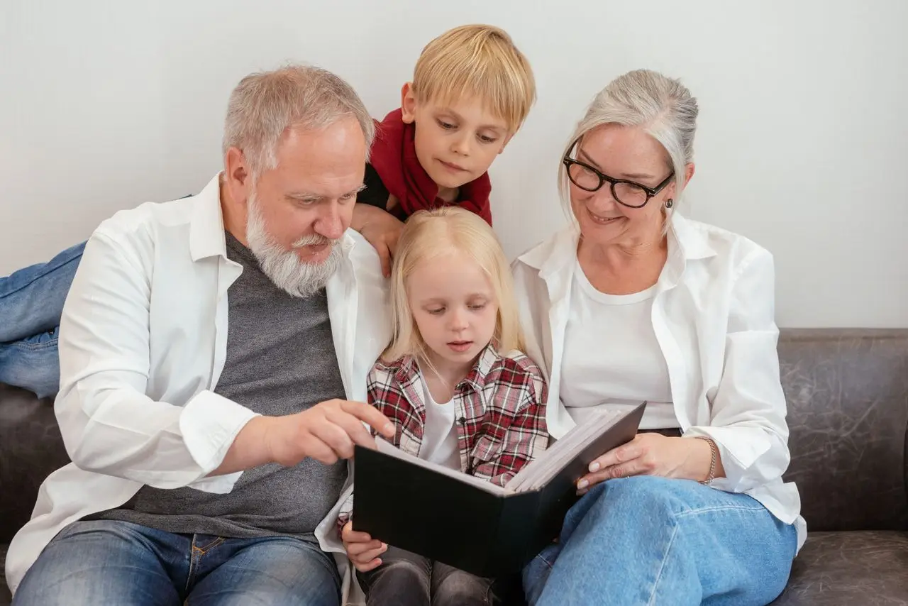 Des grands-parents feuillettent un album photo avec leurs petits-enfants