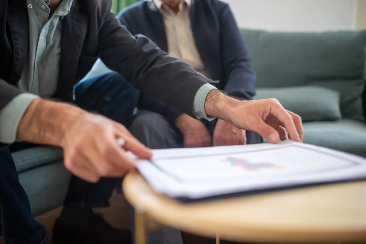 Deux personnes examinent un document ensemble, autour d’une table basse